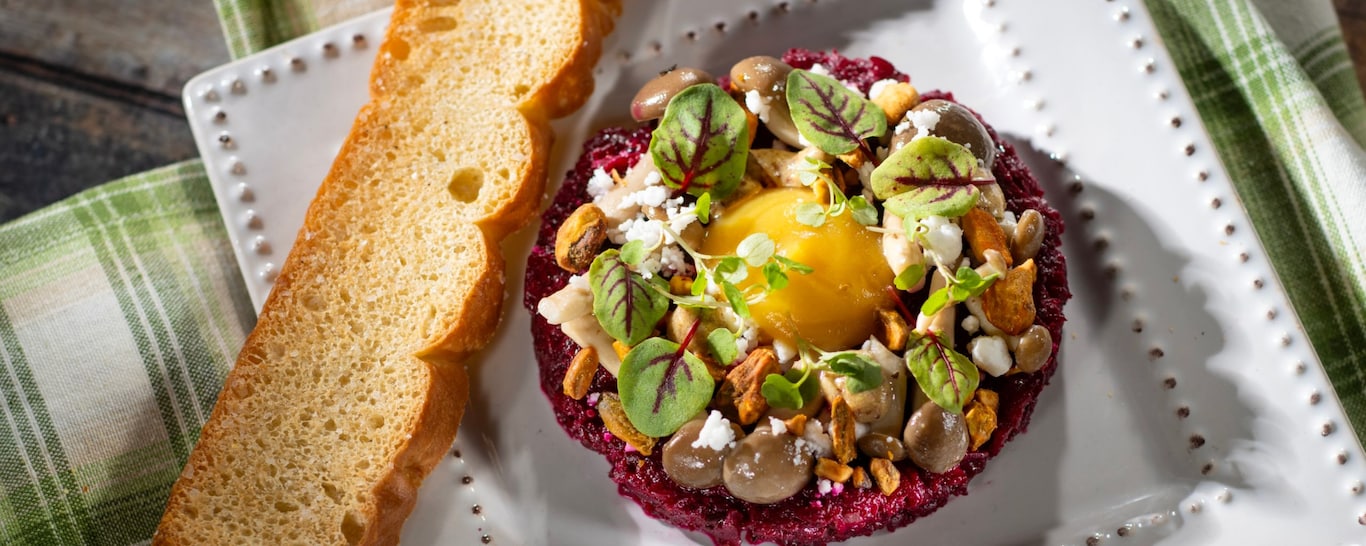 Citrus Braised Beet Tartare topped with pistachio pieces, crumbled cheese, fresh herbs and served with a slice of focaccia bread